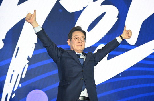 지난 4월27일 더불어민주당 제21대 대선후보로 선출된 이재명 후보가 경기 고양시 킨텍스에서 열린 '제21대 대통령선거 후보자 선출을 위한 수도권·강원·제주 경선 및 최종 후보자 선출 대회'에서 양손을 들어 인사하고 있다.<공동취재·연합뉴스 사진>